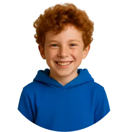 Chłopiec z rudymi włosami w niebieskiej bluzie uśmiecha się